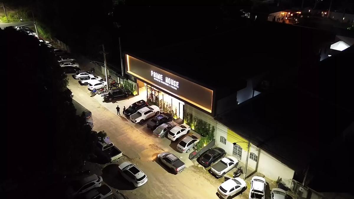 Fachada do Prime House à noite, vista de cima, com o estacionamento cheio